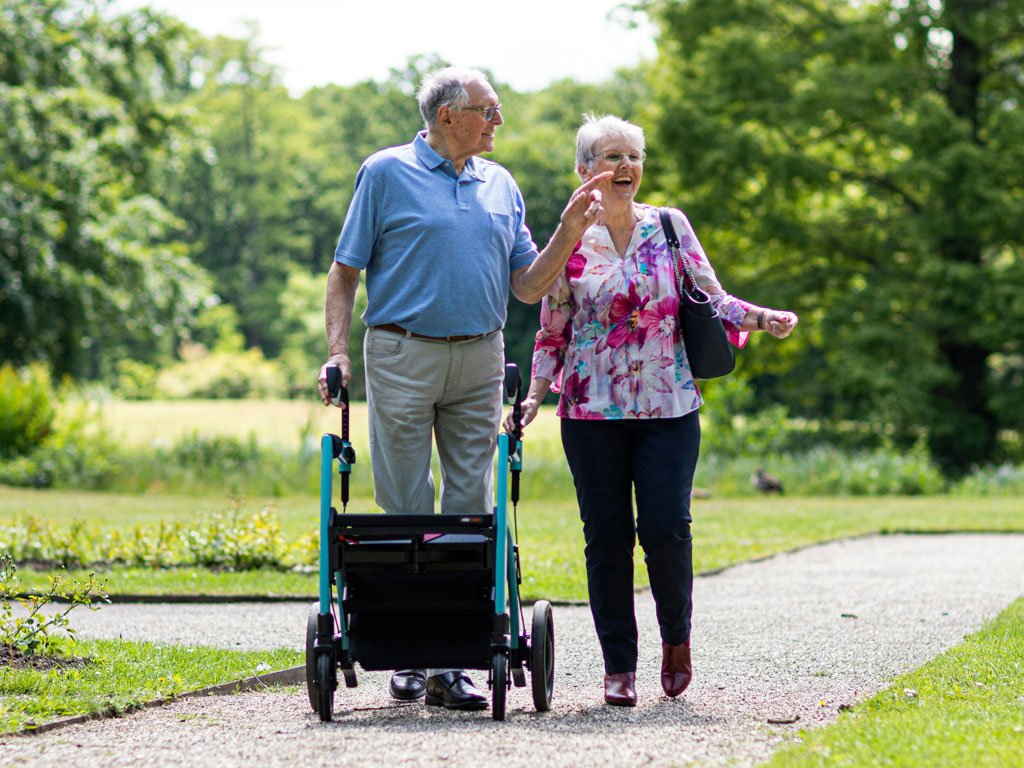 Eine Frau begleitet einen Senior mit Rollator